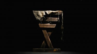 Image has a black background with a side view of a wooden manger.