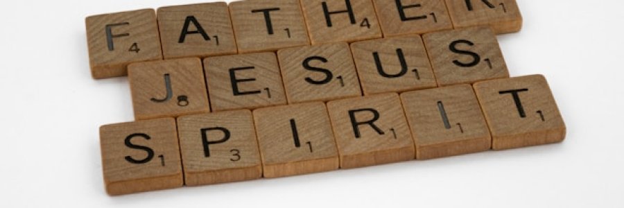 Image shows the words 'Father', 'Jesus' and 'Spirit' in wooden Scrabble tiles on a white background.